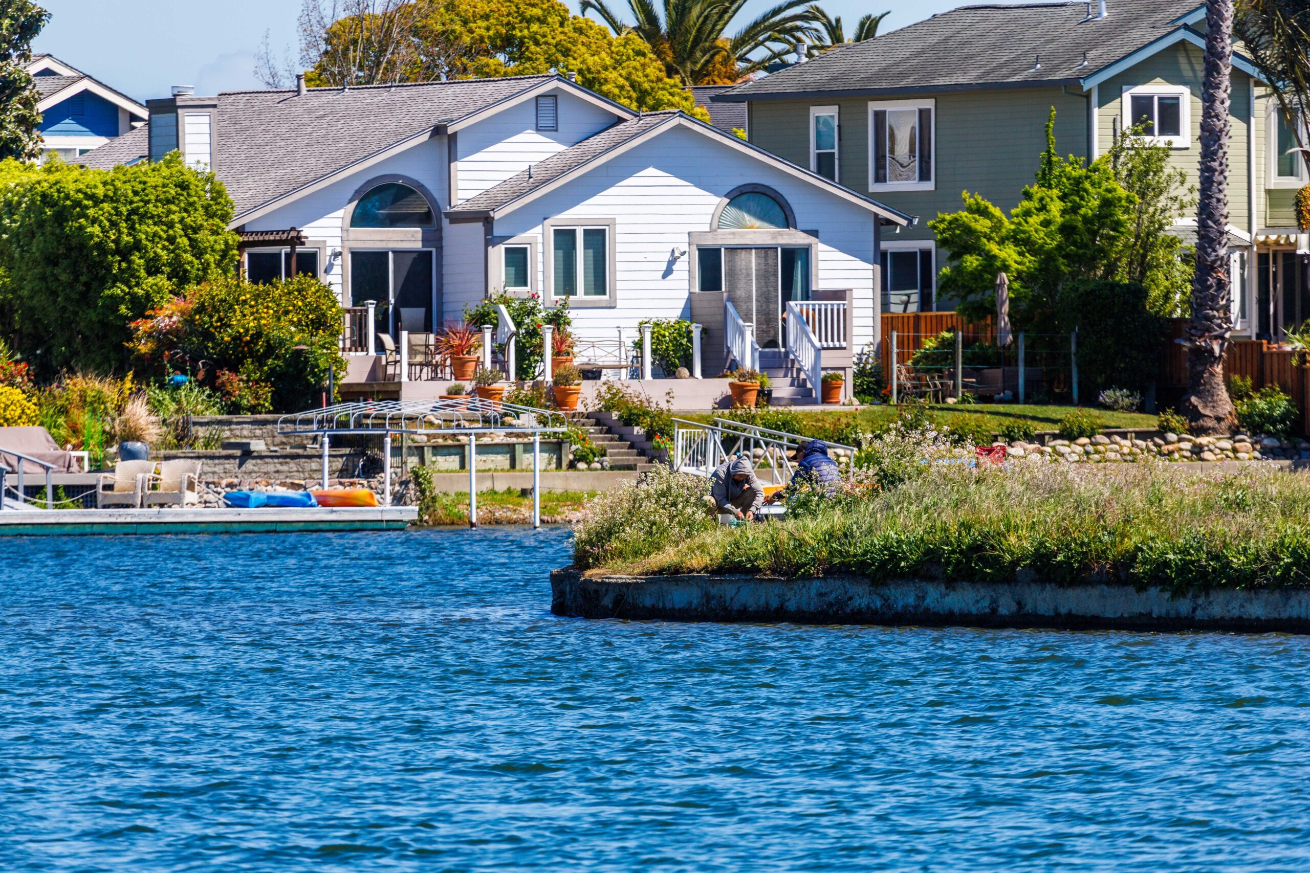 Charming lakeside house with lush garden and wooden deck, ideal for serene outdoor living.